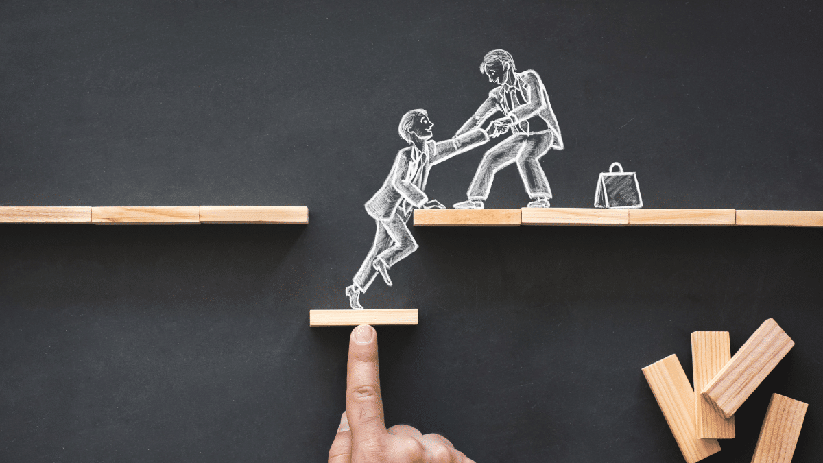 A man pulling his friend toward the top 